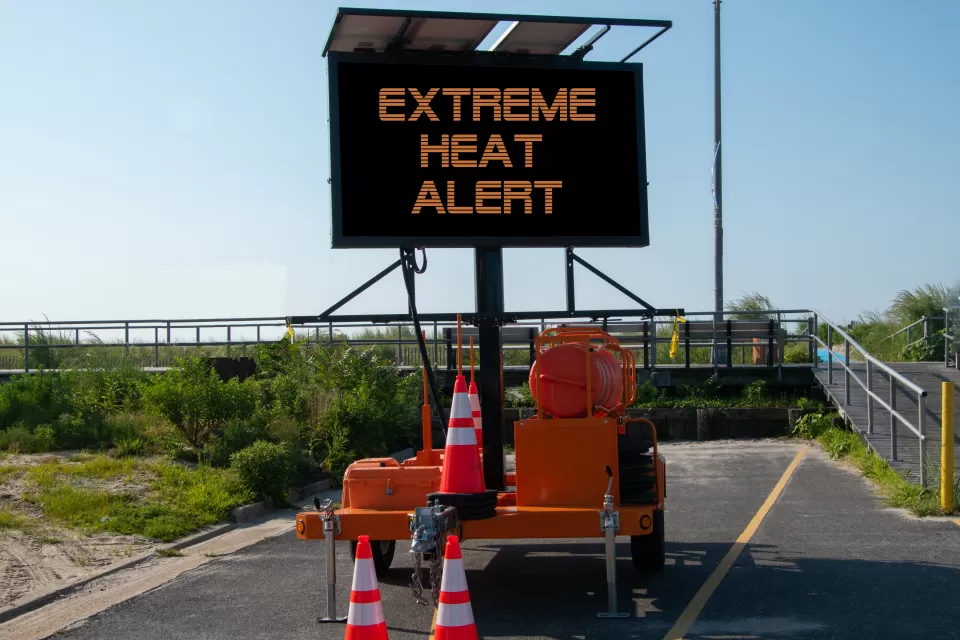 Road sign with EXTREME HEAT ALERT surrounded by orange traffic cones